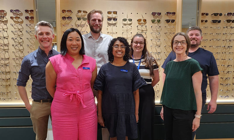 Group photo of MEC team standing in front of Glasses display